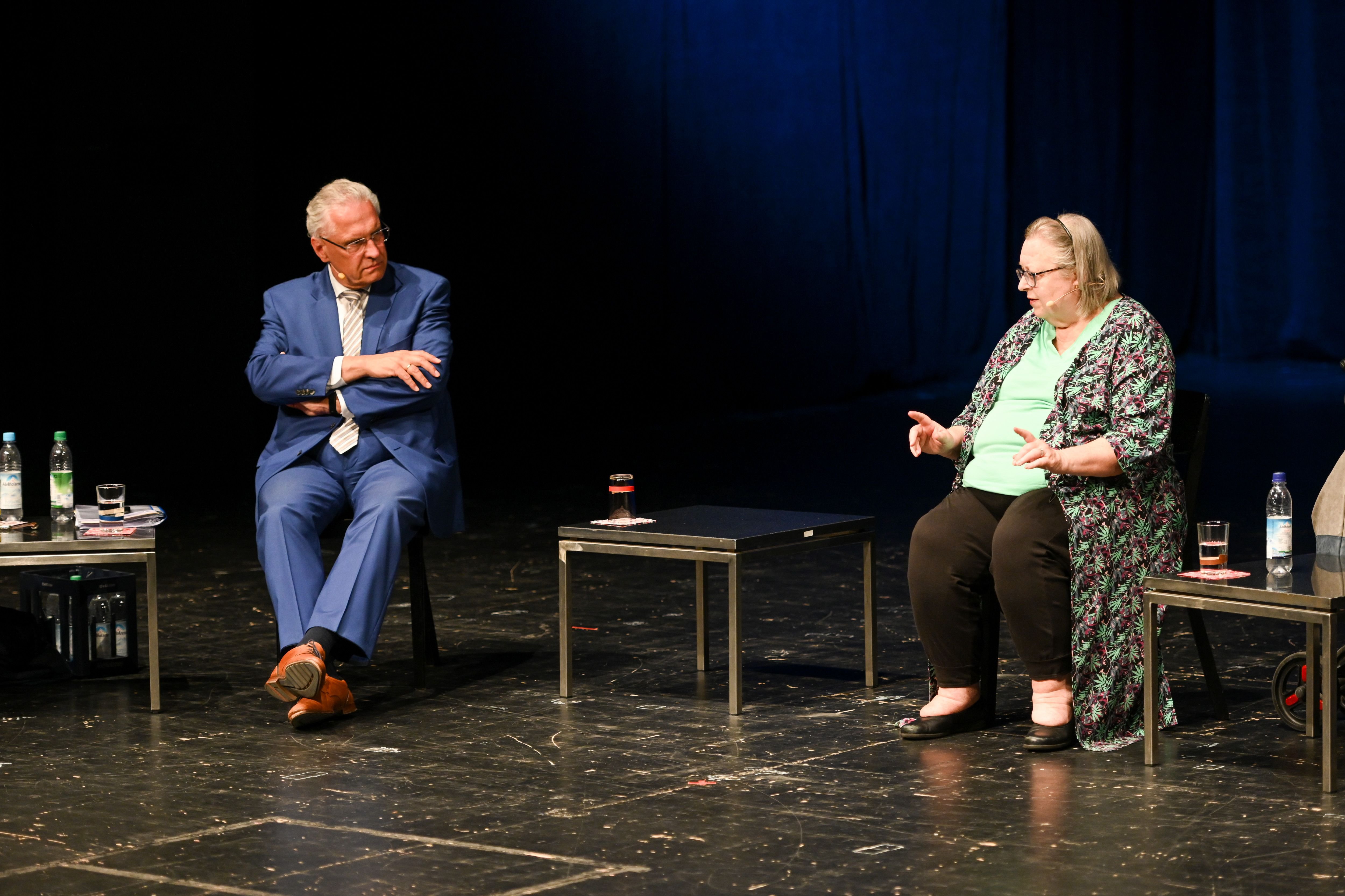 


                 Ein Mann und eine Frau sitzen auf einer Bühne und diskutieren